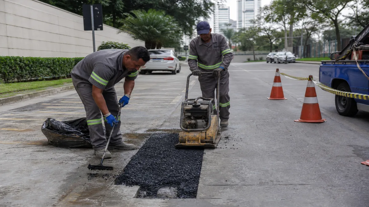 asfalto frio para manutenção de vias: Equipe aplicando asfalto frio em via após reparo de vala de rede de água, .